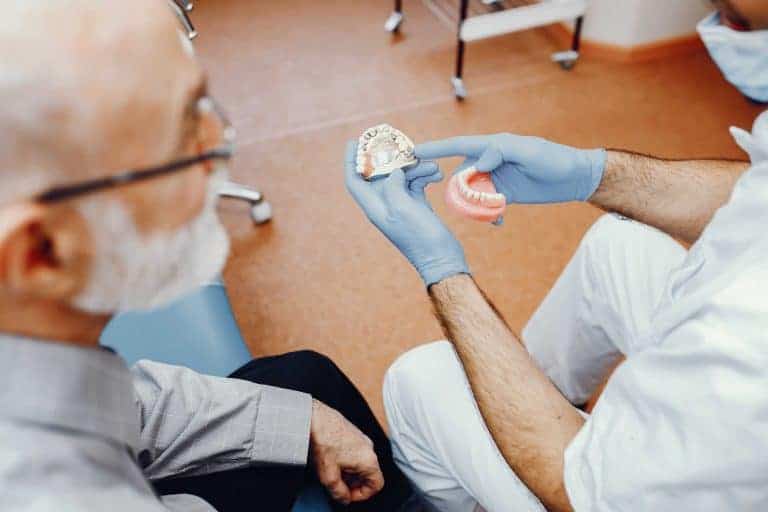 רופא שיניים מציג לבחור מבוגר שתלים בשיניים