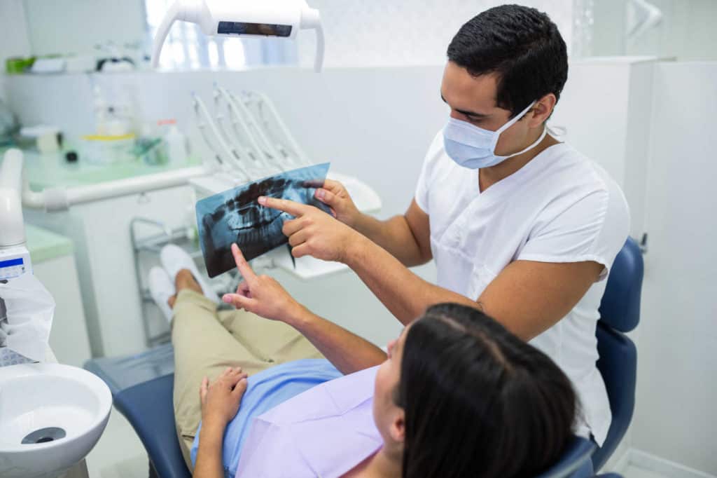 רופא שיניים מציג למטופלת צילום של חלל הפה